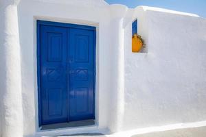 vieille porte bleue et fleurs roses, architecture grecque traditionnelle, île de santorin, grèce. beaux détails de l'île de santorin, maisons blanches, portes et volets bleus, la mer égée. photo