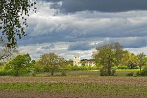 Église skipwith vu à travers un champ, North Yokshire, Angleterre photo