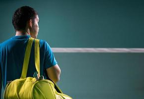 Un joueur de badminton professionnel tient son sac de badminton et sa raquette dans une cour intérieure pour un tournoi de compétition unique de badminton photo