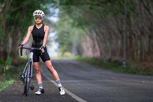 femme heureuse athlète cycliste se prépare à faire du vélo dans la rue, la route, à grande vitesse pour l'exercice passe-temps et la compétition en tournée professionnelle photo