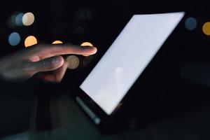 un homme d'affaires touche un smartphone ou une tablette pour le travail technologique sur le lit dans la chambre pendant le travail à domicile pour piloter la communication commerciale et financière photo