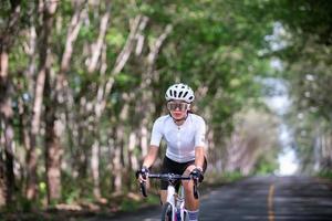 femme heureuse athlète cycliste se prépare à faire du vélo dans la rue, la route, à grande vitesse pour l'exercice passe-temps et la compétition en tournée professionnelle photo