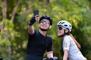 Heureux couple cycle selfies avec téléphone intelligent pendant le trajet en campagne pour le style de vie de la santé