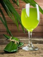 le pandan et le jus de pandan sont fabriqués à partir de broyés ou bouillis. c'est une boisson saine dans un verre transparent placé sur un sol en bois.tourné en studio.vue rapprochée photo