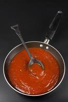 la sauce tomate est préparée pour cuire comme des spaghettis ou des pâtes à l'italienne dans une poêle noire sur fond noir.vue de dessus photo