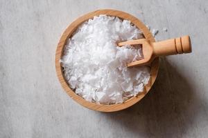 fleur de sel, est un sel qui se forme comme une fine croûte délicate à la surface de l'eau de mer dans la cuillère en bois et le bol en bois sur fond de bois. mise au point sélective. photo