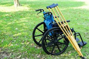 les béquilles s'appuient contre le fauteuil roulant dans le parc ou la pelouse. concept de soins de santé et médical. photo