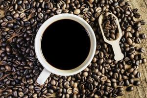 café noir dans la tasse, grains de café noirs sur le vieux parquet, gros plan de graines de café. photo