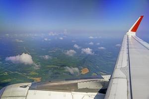 les ailes des avions pendant le vol regardent depuis la fenêtre du passager. il y a des nuages blancs dans le ciel bleu. photo