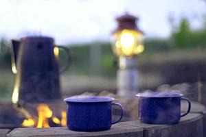 bouilloire en émail vintage sur le poêle à bois le matin camping.bouilloire à café antique. feu de joie dans la campagne.soft focus. photo