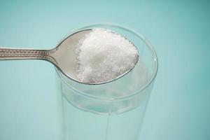 verser du sucre blanc dans un verre d'eau sur la table photo