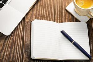 ordinateur portable, journal et tasse à café sur une table en bois. photo