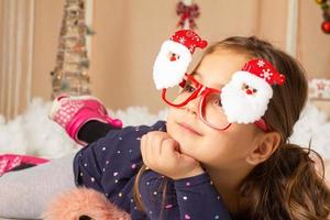 petite fille portant des lunettes de père noël et faisant des grimaces photo