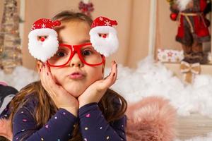 petite fille portant des lunettes de père noël et faisant des grimaces photo