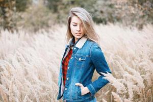 jeune fille en vêtements jeans et une chemise à carreaux rouge dans le champ d'automne avec de l'herbe photo