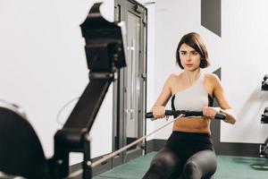 femme faisant de l'exercice sur un rameur, faisant partie d'une séance de cardio d'échauffement en circuit photo