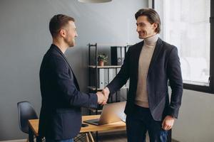 deux jeunes hommes d'affaires souriants et prospères se serrant la main lors d'une réunion d'affaires au bureau photo