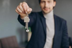 portrait d'un agent immobilier professionnel joyeux tenant un presse-papiers et montrant les clés en main, mise au point sélective. photo