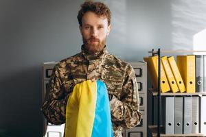 soldat patriote ukrainien en uniforme militaire tenant un drapeau jaune et bleu au bureau photo