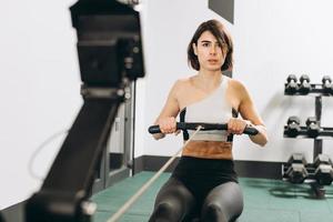 femme faisant de l'exercice sur un rameur, faisant partie d'une séance de cardio d'échauffement en circuit photo