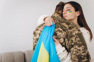 une fille ukrainienne embrasse et tient un drapeau jaune et bleu d'un militaire en uniforme et lui dit au revoir. photo