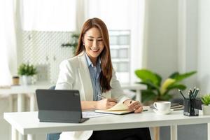 belle jeune fille asiatique travaillant dans un espace de bureau avec un ordinateur portable. concept d'entreprise féminine intelligente. photo
