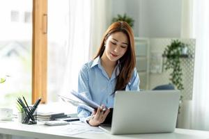 belle jeune femme utilisant son ordinateur portable assise sur une chaise sur son lieu de travail. photo