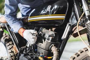 mécanicien vérifie la bougie d'allumage de la moto dans le garage de l'atelier, l'homme répare la moto dans l'atelier de réparation, les concepts de réparation et d'entretien photo