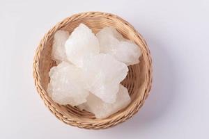 Le sucre candi dans un panier en osier sur un fond blanc photo