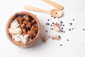 Riz frit au poulet et au poivre à l'ail dans des tasses en bois sur fond blanc photo