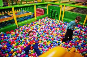 enfant jouant dans une fosse à balles colorée. garderie aire de jeux intérieure. piscine à balles pour les enfants. jardin d'enfants ou salle de jeux préscolaire. photo