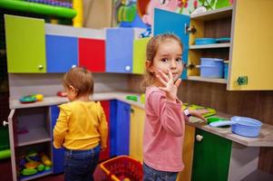 jolies soeurs jouant dans un centre de jeux intérieur. jardin d'enfants ou salle de jeux préscolaire. dans la cuisine des enfants. photo