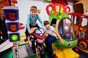 deux frères assis sur une moto et une attraction d'hélicoptère dans l'aire de jeux. photo