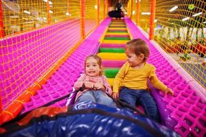 deux sœurs assises dans des beignets de tube profitant de toboggans dans un centre pour enfants amusant. photo