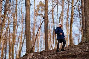 jeune garçon porte une veste et un chapeau dans la forêt du début du printemps. photo