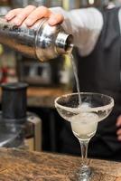barman au travail, préparation de cocktails. verser la margarita dans un verre à cocktail.