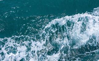 belles vagues de mer avec mousse de couleur bleue et turquoise. eau de mer bleue abstraite avec vague blanche. vagues bleues et blanches de la route du navire sur l'océan de la mer d'eau. photo