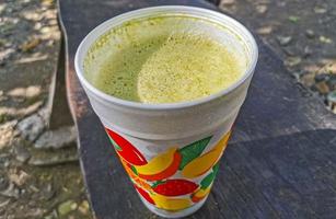 jus de smoothie vert sur banc dans un fond en bois de parc. photo