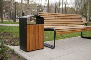 banc en bois et poubelle dans le parc du printemps sur fond d'arbres. photo