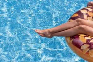 les jambes des femmes dans la piscine sur l'anneau de natation photo