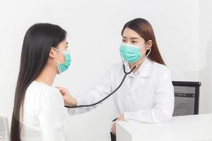 une femme médecin asiatique examine les symptômes de sa patiente tandis que les deux portent un masque médical pour prévenir la maladie infectieuse covid 19 à l'hôpital. photo