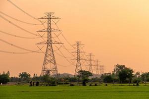 disposition du poteau haute tension, tour de transmission sur la rizière au coucher du soleil photo