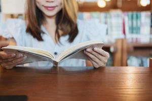 jeune femme asiatique lisant un livre dans la bibliothèque photo