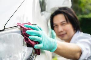 nettoyage de voiture. homme de main dans des gants nettoyant les phares de la voiture et des lingettes pour briller. photo