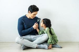 père heureux jouant à la loupe avec une fille à la maison photo