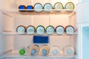 canettes de boissons gazeuses colorées et soda froid ou eau minérale à l'intérieur du réfrigérateur dans la chambre d'hôtel. photo