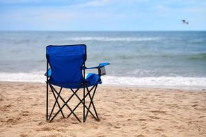chaise pliante bleue sur la plage de la mer, sans personne, vacances à la plage seules, solitude photo