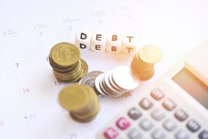 calculatrice et pile de pièces sur le calendrier avec la dette sur salaire au bureau comptage financier - concept de gestion de la dette photo