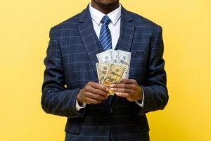 homme d'affaires nous tenant de l'argent en dollars dans les mains sur fond jaune isolé photo