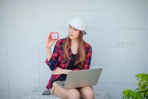 une femme ingénieur en construction regardant une montre et un ordinateur portable photo